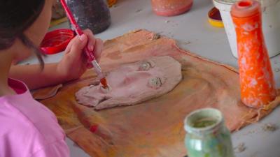 Дете осликава маску од глине